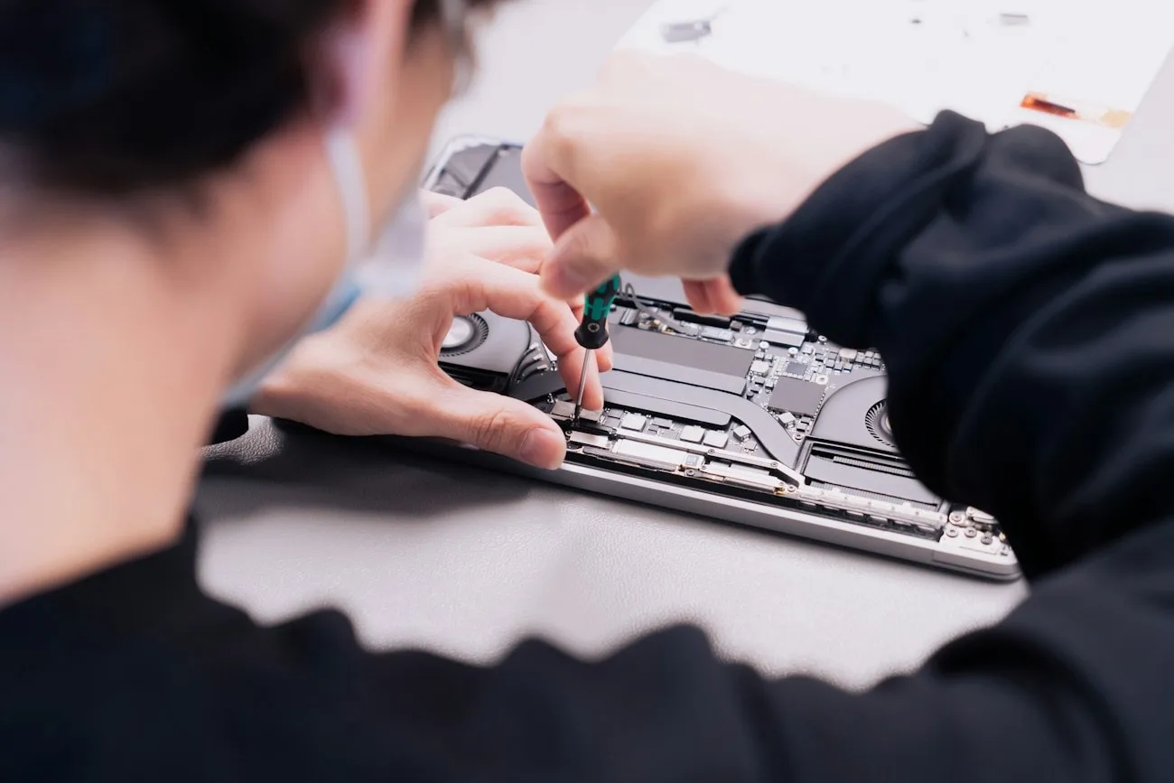 Two LaptopHaber engineers working together on a stripped-down laptop at the repair bench
