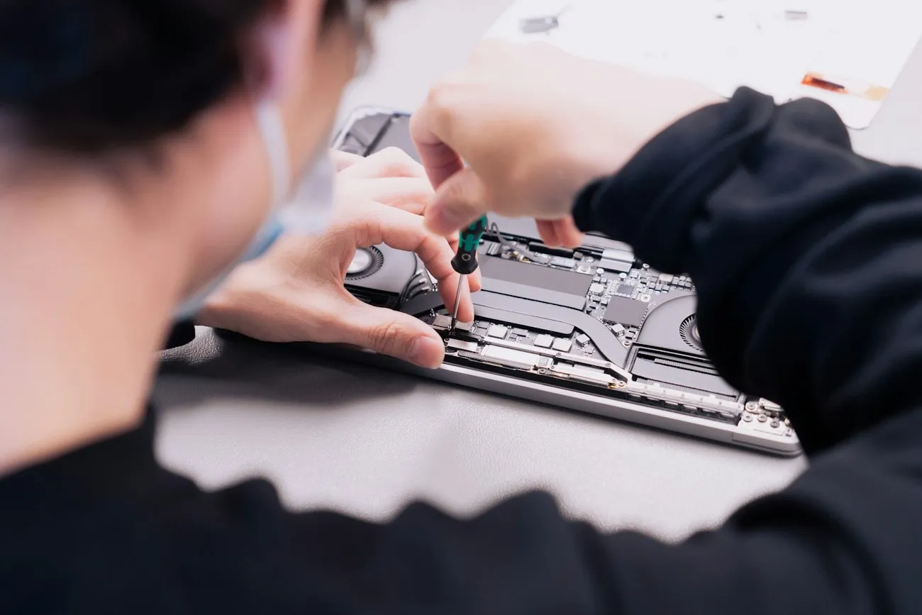 Two LaptopHaber engineers working on a stripped-down laptop at the repair bench