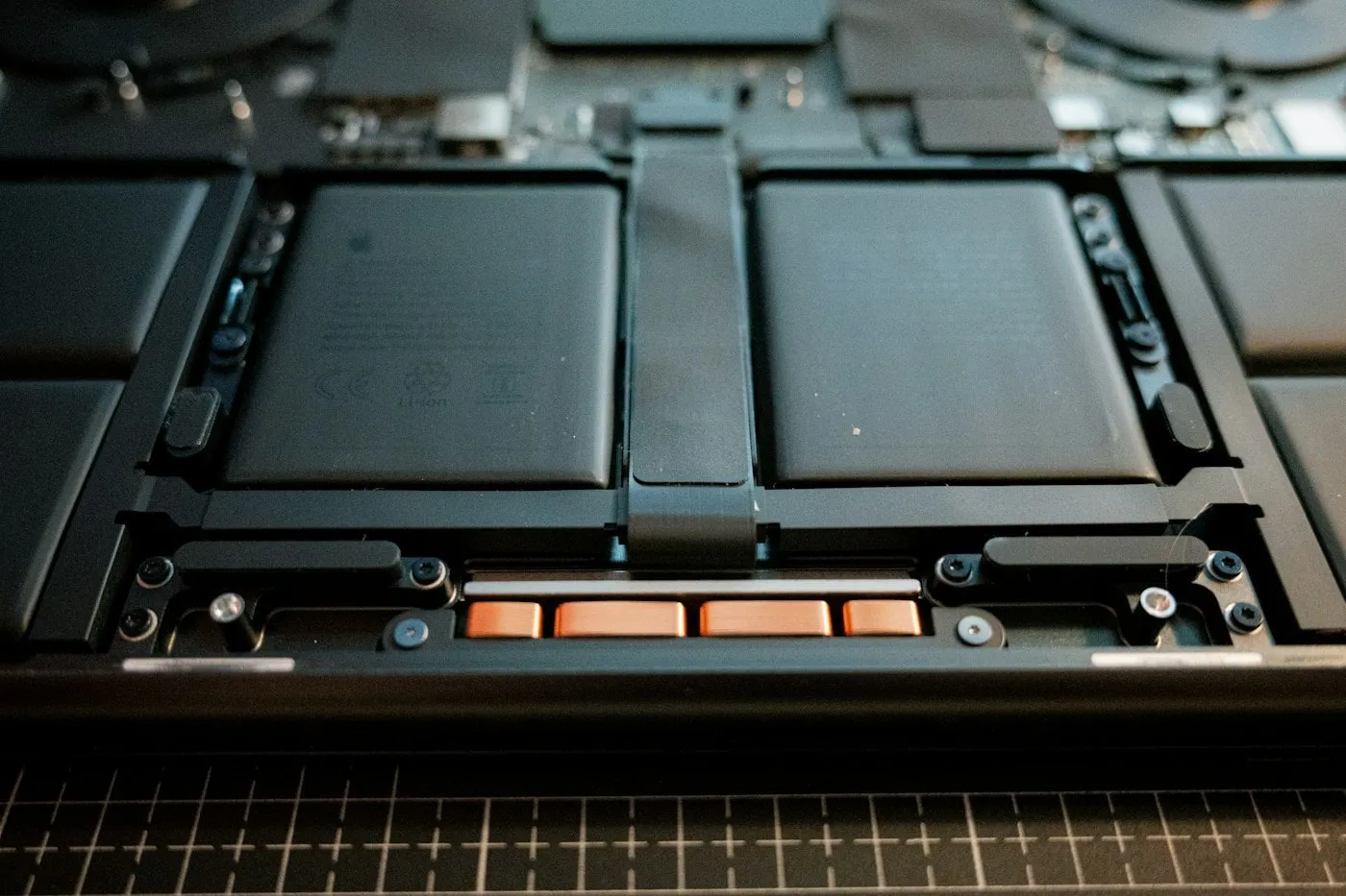 The internal lithium-ion battery cells of a laptop exposed inside the opened chassis