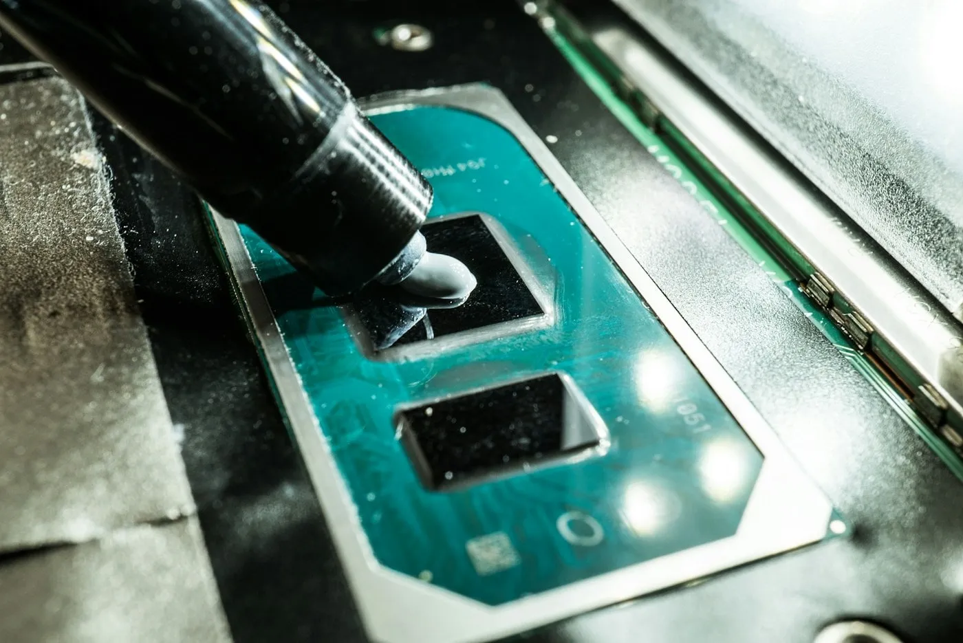 Fresh thermal compound being applied to a laptop processor die during a cooling service