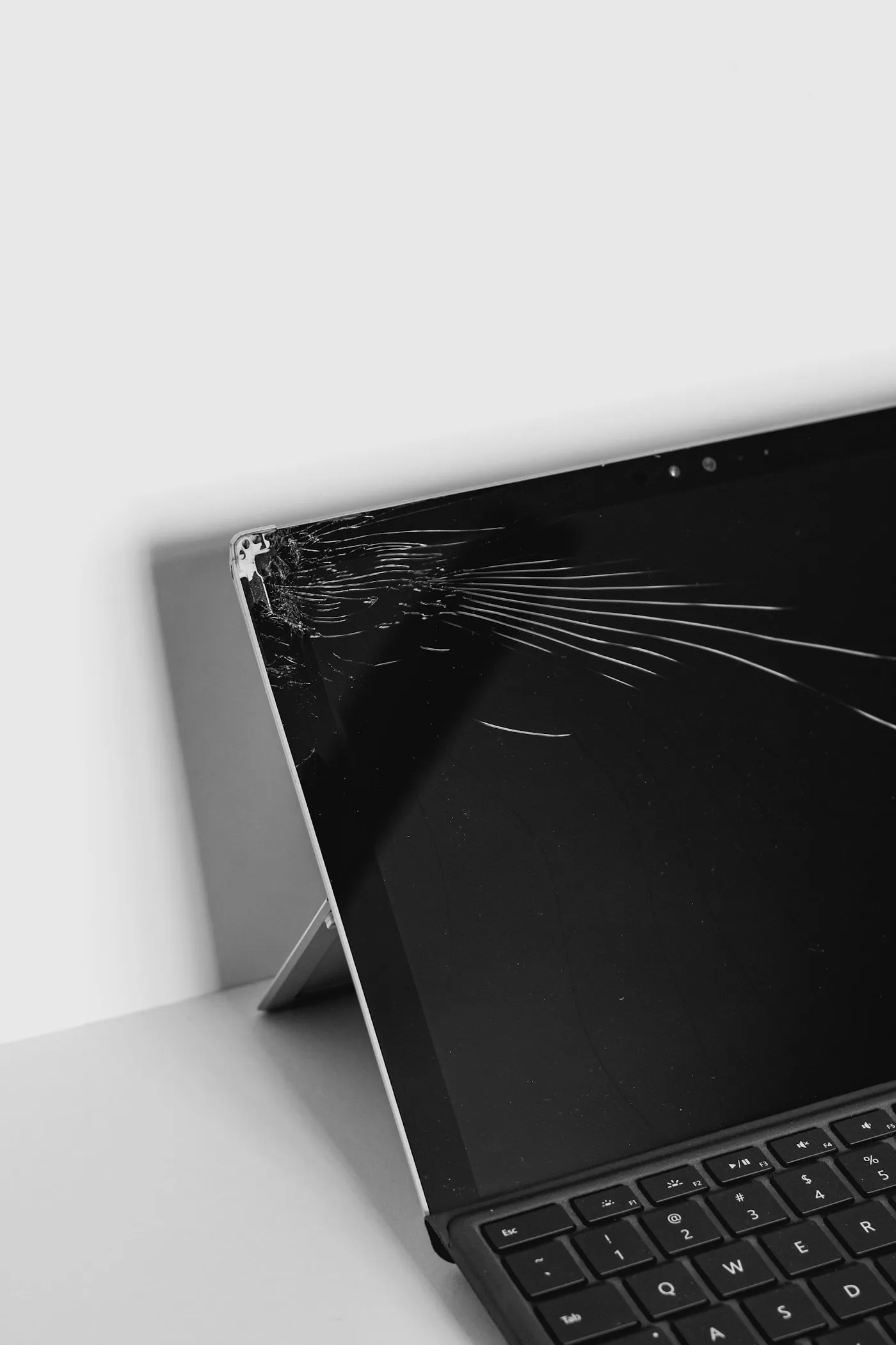 A laptop with a spidered crack radiating across the top corner of its display