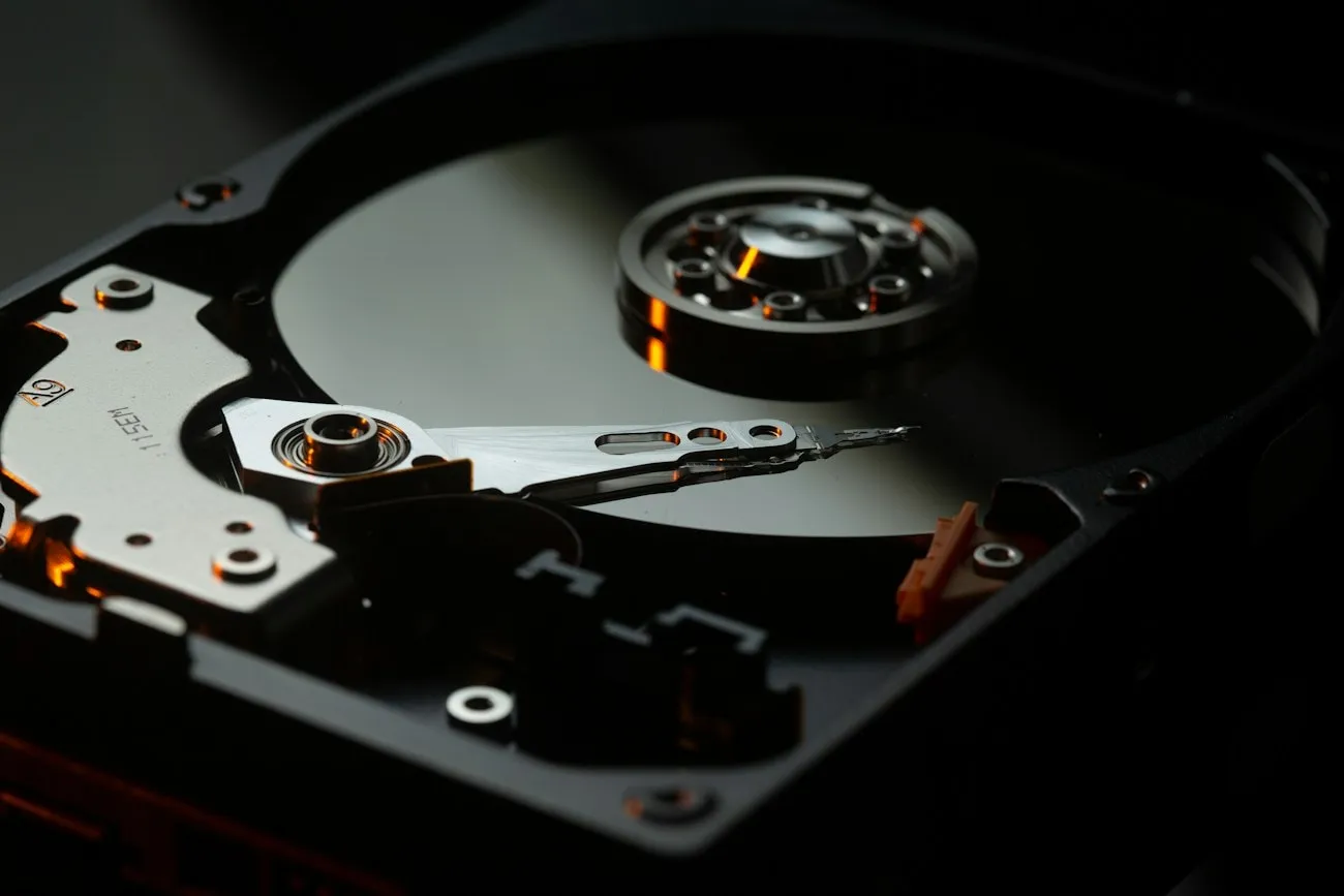 The exposed platter and actuator arm of a hard drive opened on the bench for data recovery