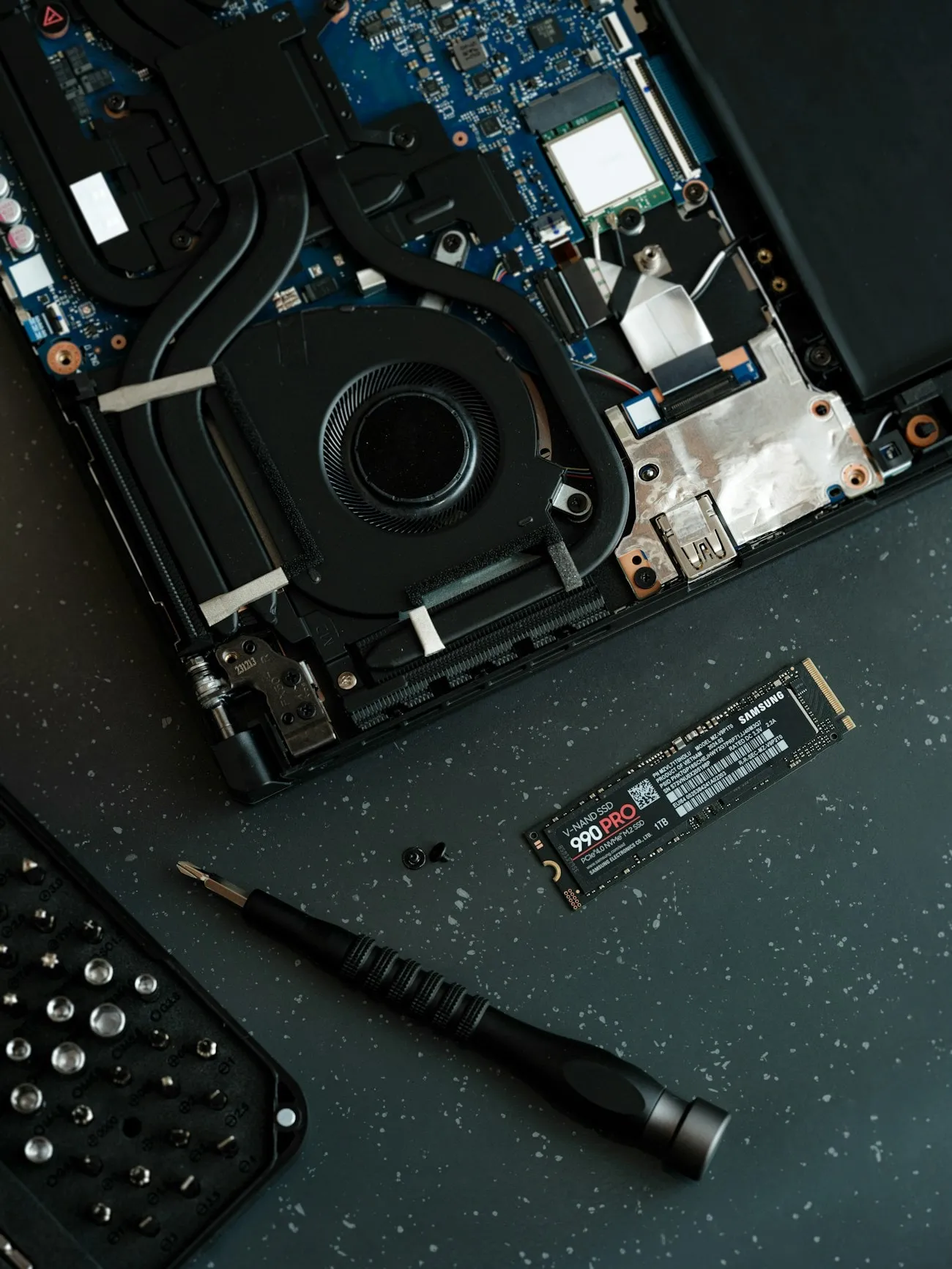 A Samsung NVMe solid-state drive lying beside an opened laptop during a storage upgrade