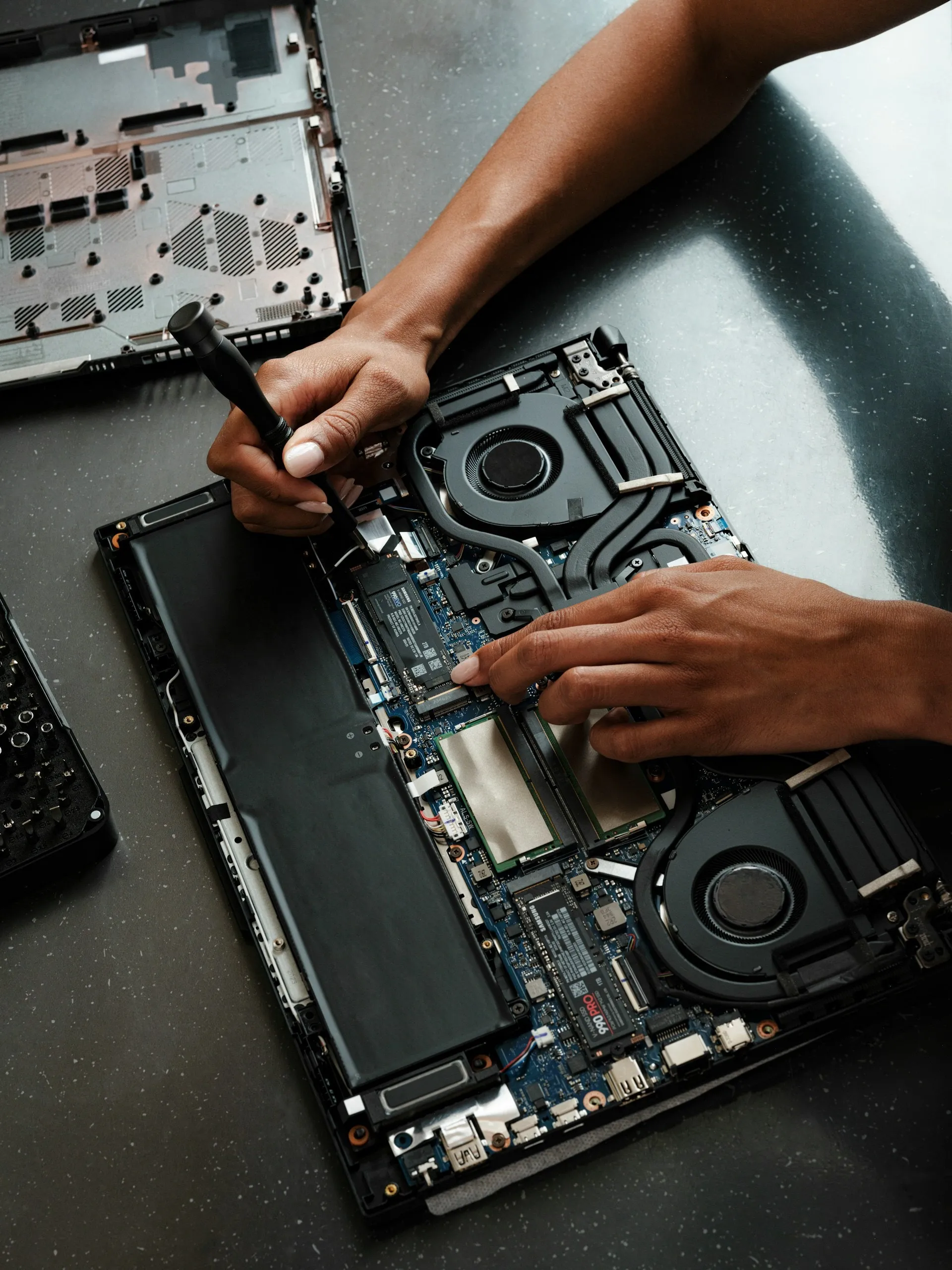 Hands working with a precision tool inside an opened laptop chassis
