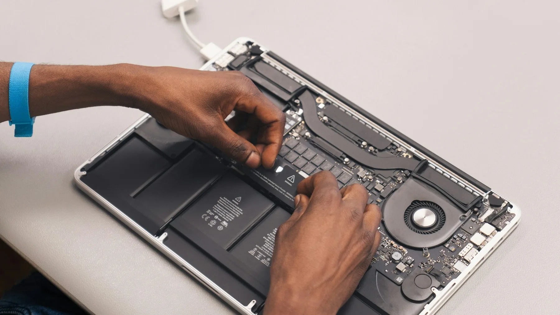 A LaptopHaber engineer lifting the battery assembly out of an opened laptop on the workshop bench