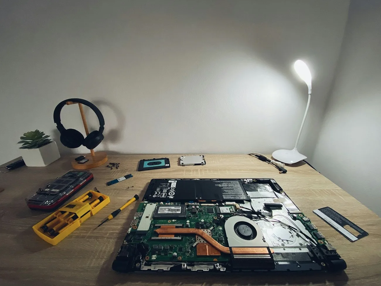 Precision screwdrivers and hand tools laid out beside a stripped-down laptop on a LaptopHaber diagnostic bench